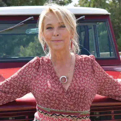 Woman wearing Effie - Ford pickup earrings and necklace standing in front of a red vintage Ford pickup truck