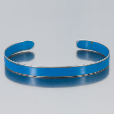 The Perry - Mazda pickup bracelet features a simple silver design with bright blue enamel inlay, adjustable for comfort. Displayed on a reflective light gray background. Enjoy free shipping on this stylish accessory.