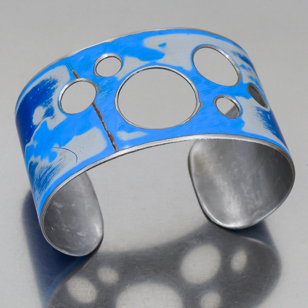 Adjustable Ira bracelet made from 75 Ford pickup metal with original blue car paint and circular cutout design.