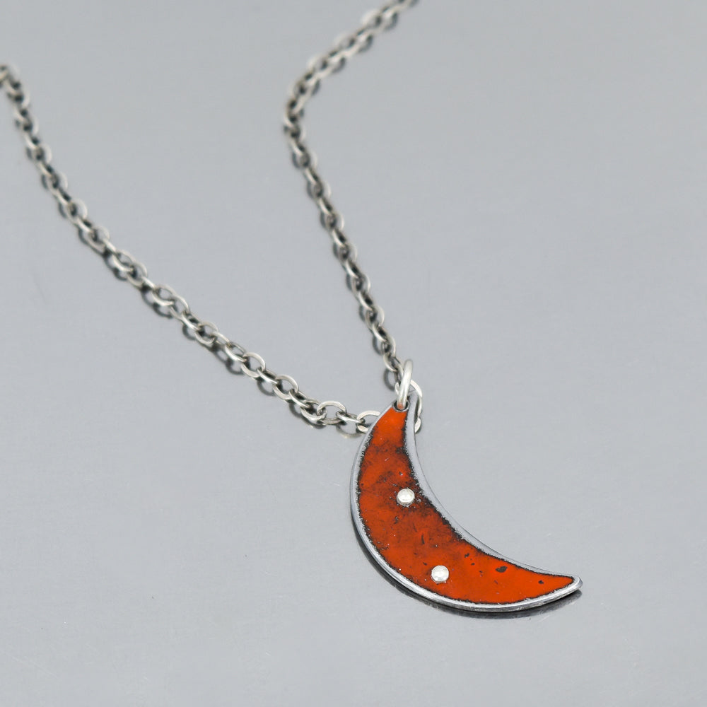 Close-up of a crescent-shaped pendant made from original 69 Ford Maverick paint on an 18-inch sterling silver chain