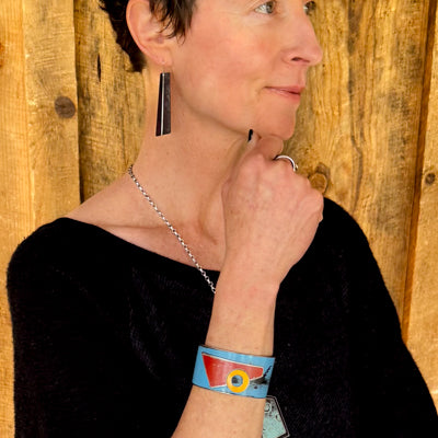 Woodrow - Chevy, Toyota, Ford bracelet worn on wrist with blue, red, and yellow pickup truck designs against wooden background.