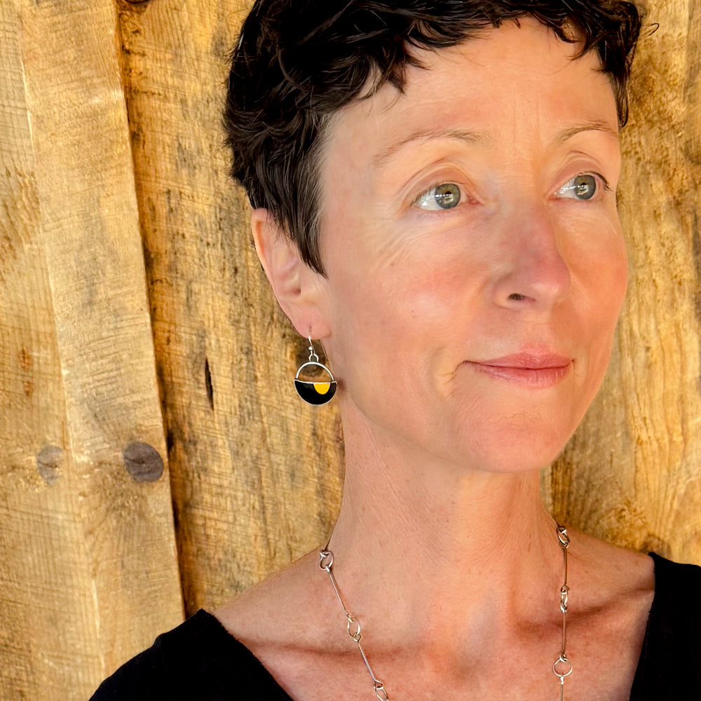 Woman modeling jewelry, wearing a bright, colorful, unique, original necklace and earrings.
handmade using vintage car parts with the original car paint intact. Joyride Jewelry. Jewelry made from vintage car parts. sustainable, recycled