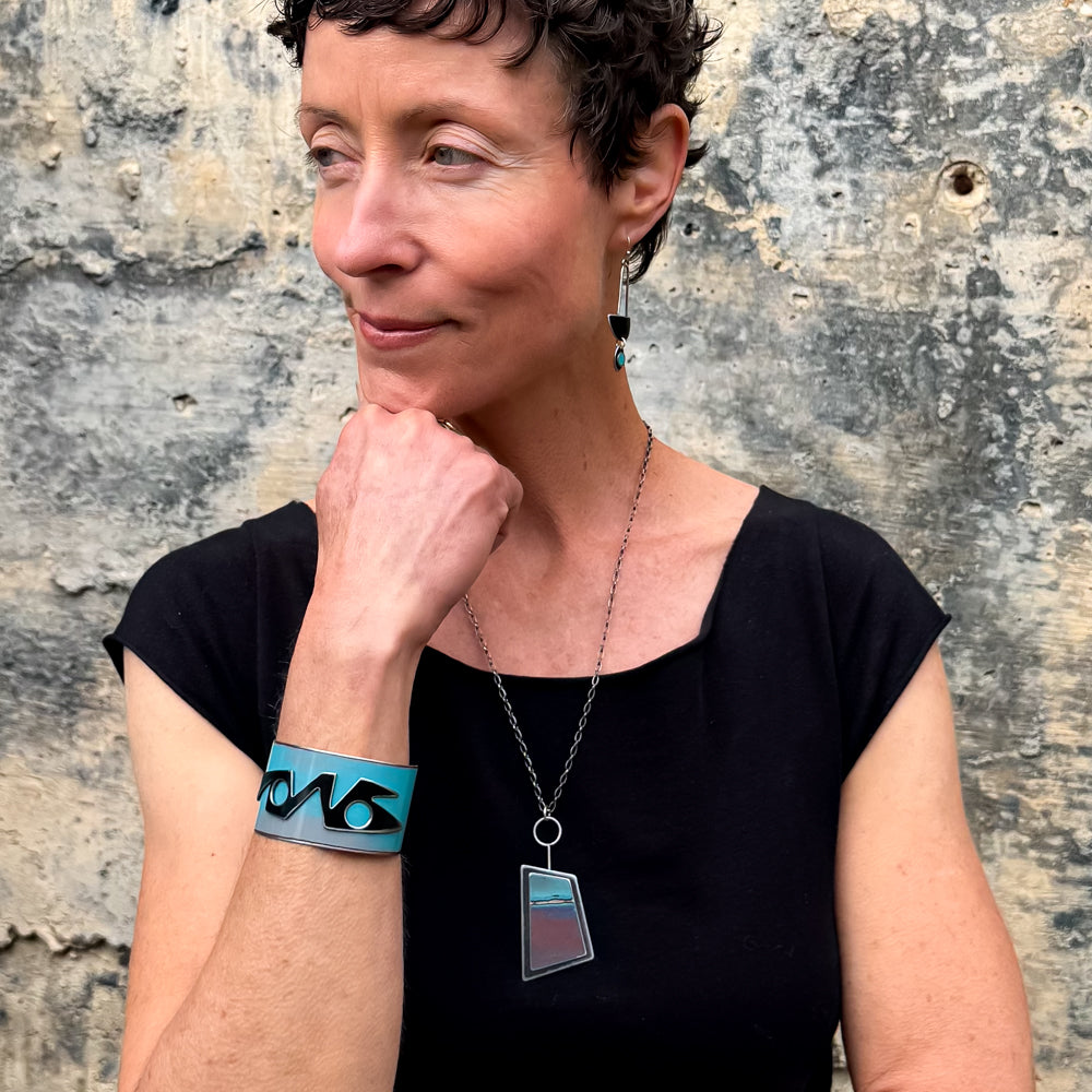 Woman wearing Vern Ford Thunderbird turquoise bracelet and matching necklace against rustic wall background