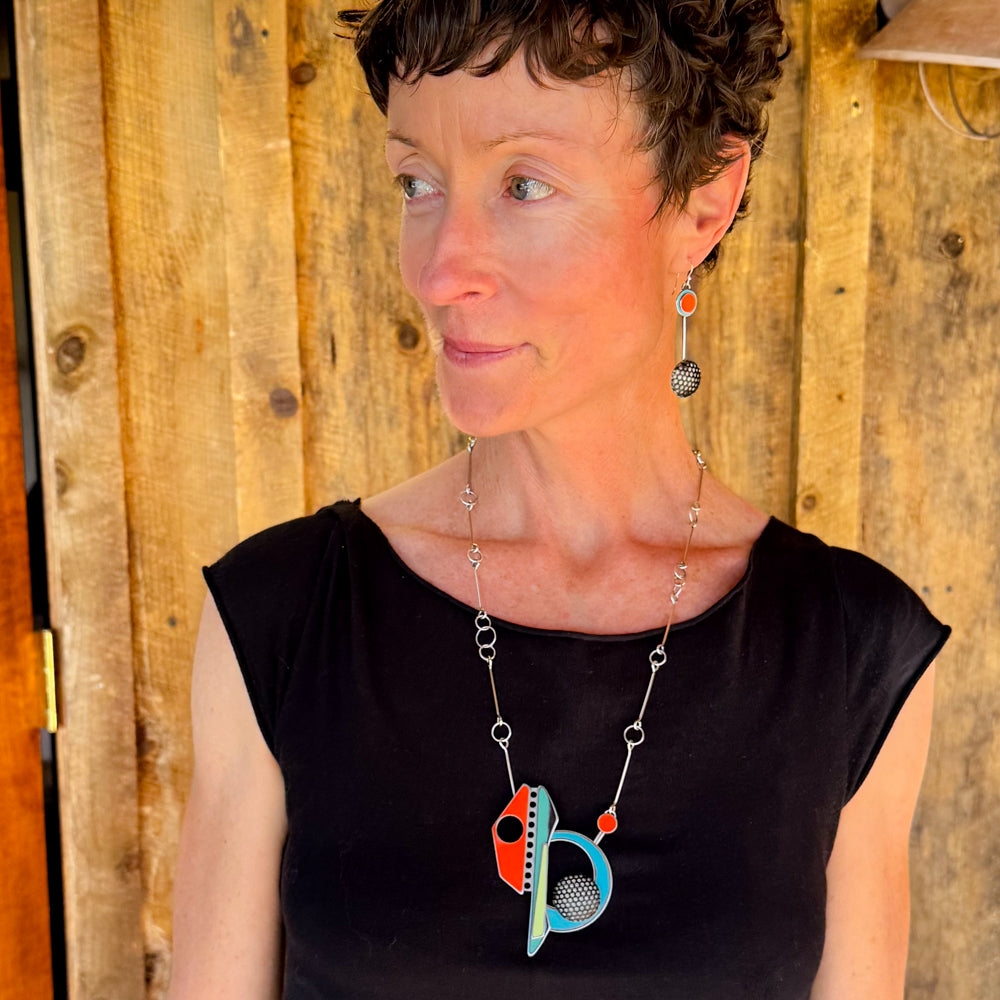 Woman wearing a long oxidized sterling silver chain necklace with colorful vintage car paint pendants and matching earrings.