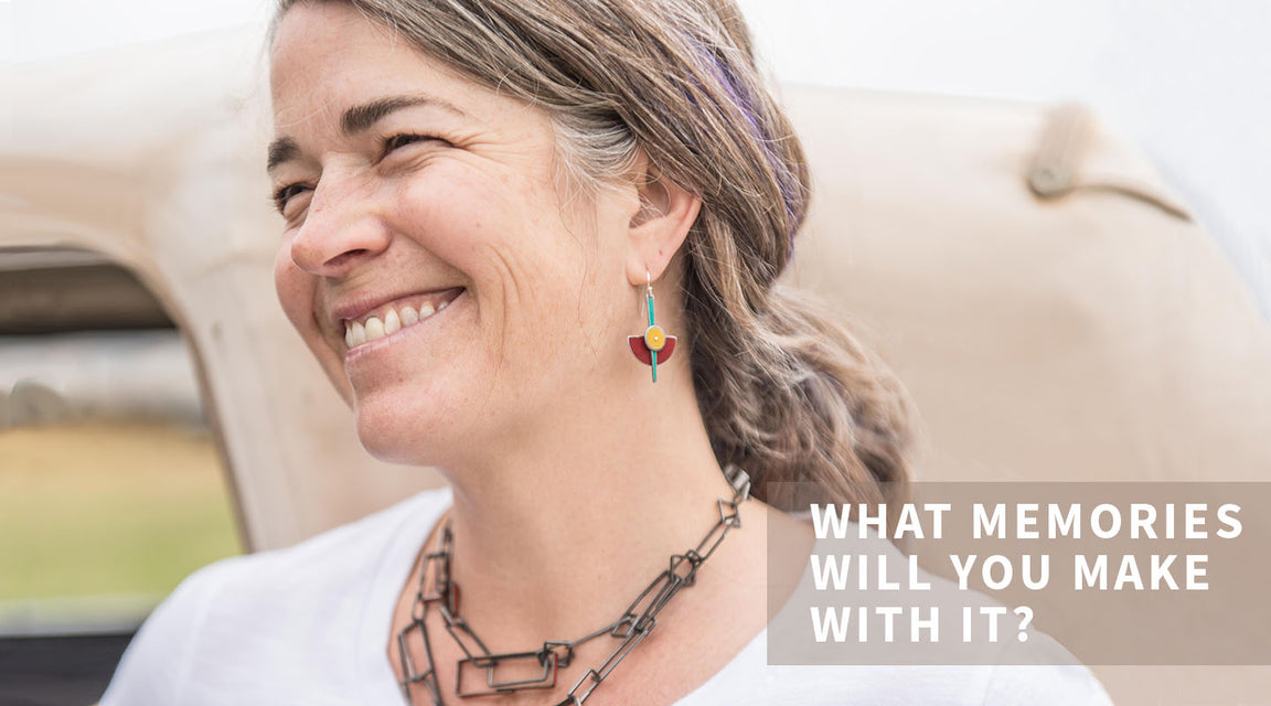 A smiling woman with gray-streaked hair wears colorful heart-shaped earrings and a geometric necklace crafted from vintage car parts. Text in the image reads: WHAT MEMORIES WILL YOU MAKE WITH IT?.