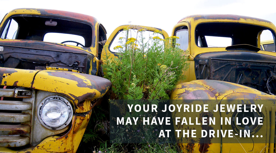 Two old, rusted yellow trucks with original paint sit abandoned in tall grass and wildflowers. Overlay text reads: “Your joyride jewelry may have fallen in love at the drive-in…”.