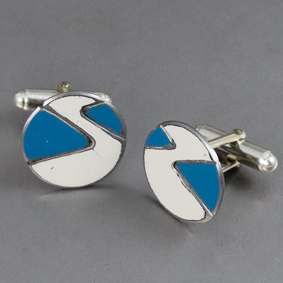 Maynard - Ford & Mazda: Round cufflinks with a white and blue geometric design and silver edges, displayed on a gray surface—sophisticated accessories inspired by vintage Ford and Mazda car parts.