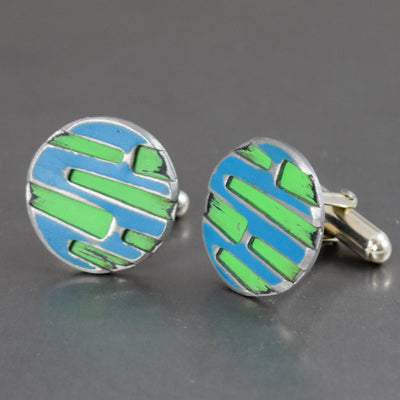 The Hugh - Ford & Mazda cufflinks feature a geometric blue and green enamel design on silver-toned metal, inspired by vintage car parts and original paint details, presented on a gray background.