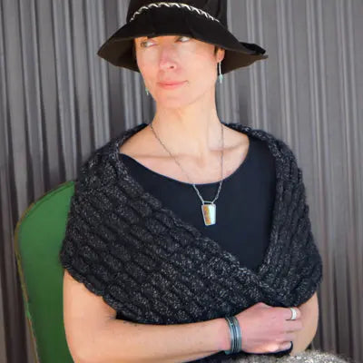 Norbert - Ford pickup bracelet worn on wrist with black knit shawl and black hat against gray background