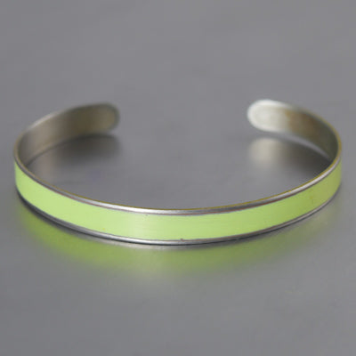 The Oliver- Plymouth Satellite is a silver cuff bracelet featuring a smooth, light yellow-green enamel strip inspired by vintage car paint, shown on a simple gray background.