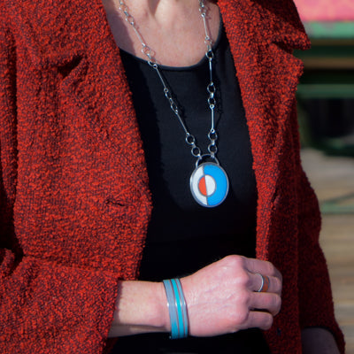 Louie - Ford Thunderbird bracelet on wrist with red coat and black shirt background in natural light.