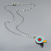 The Fannie - Ford, Dodge, Oldsmobile necklace features a modern pendant with concentric turquoise, white, and red circles and black and yellow petal shapes on gray, all hanging from an oxidized sterling silver chain.