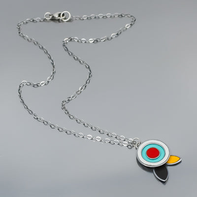 The Fannie - Ford, Dodge, Oldsmobile necklace features a modern pendant with concentric turquoise, white, and red circles and black and yellow petal shapes on gray, all hanging from an oxidized sterling silver chain.