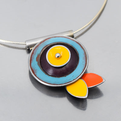 The Verna - Ford & Mercury pendant necklace features blue, brown, and yellow rings with yellow and orange petal accents on a sterling silver cable, echoing elegant vintage Ford Thunderbird style.