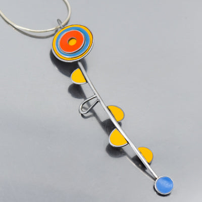 The Wonda - Ford & AMC pendant necklace features a stainless stem with yellow semicircles, a red, orange, and blue circular top, and a solid blue circle bottom. Comes with a sterling silver chain and free shipping.  Reminiscent of a flower this is a handmade original design by Joyride Jewelry made from vintage car parts. 