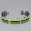 The Oliver-Plymouth Satellite is a sleek, metallic adjustable bracelet featuring a smooth light green enamel strip at the center, shown on a reflective gray surface. Enjoy free shipping on this elegant accessory.