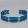 The Perry - Mazda Pickup is a metallic cuff bracelet featuring a smooth, vibrant blue enamel outer surface, displayed on a reflective gray background. Enjoy free shipping on this standout accessory.