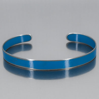 The Perry - Mazda Pickup is a metallic cuff bracelet featuring a smooth, vibrant blue enamel outer surface, displayed on a reflective gray background. Enjoy free shipping on this standout accessory.