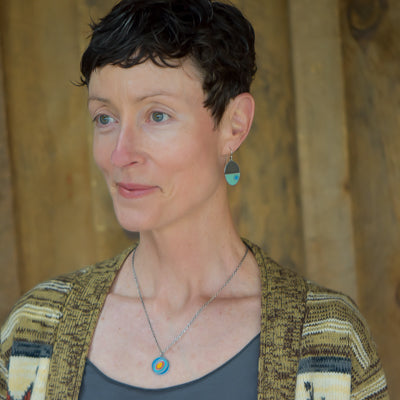 Earnestine - Ford & Mazda necklace and matching earrings worn by woman against wooden background