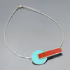 Lana - Ford & Dodge: A necklace with a turquoise circle pendant overlapped by a red horizontal bar, hanging from a sleek sterling silver cable chain. Jewelry made from vintage cars with the original car paint intact.