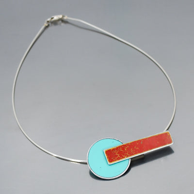 Lana - Ford & Dodge: A necklace with a turquoise circle pendant overlapped by a red horizontal bar, hanging from a sleek sterling silver cable chain. Jewelry made from vintage cars with the original car paint intact.