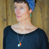Woman wearing Beverly - Plymouth & Ford pendant necklace featuring orange, turquoise, and green car paint with sterling silver chain.