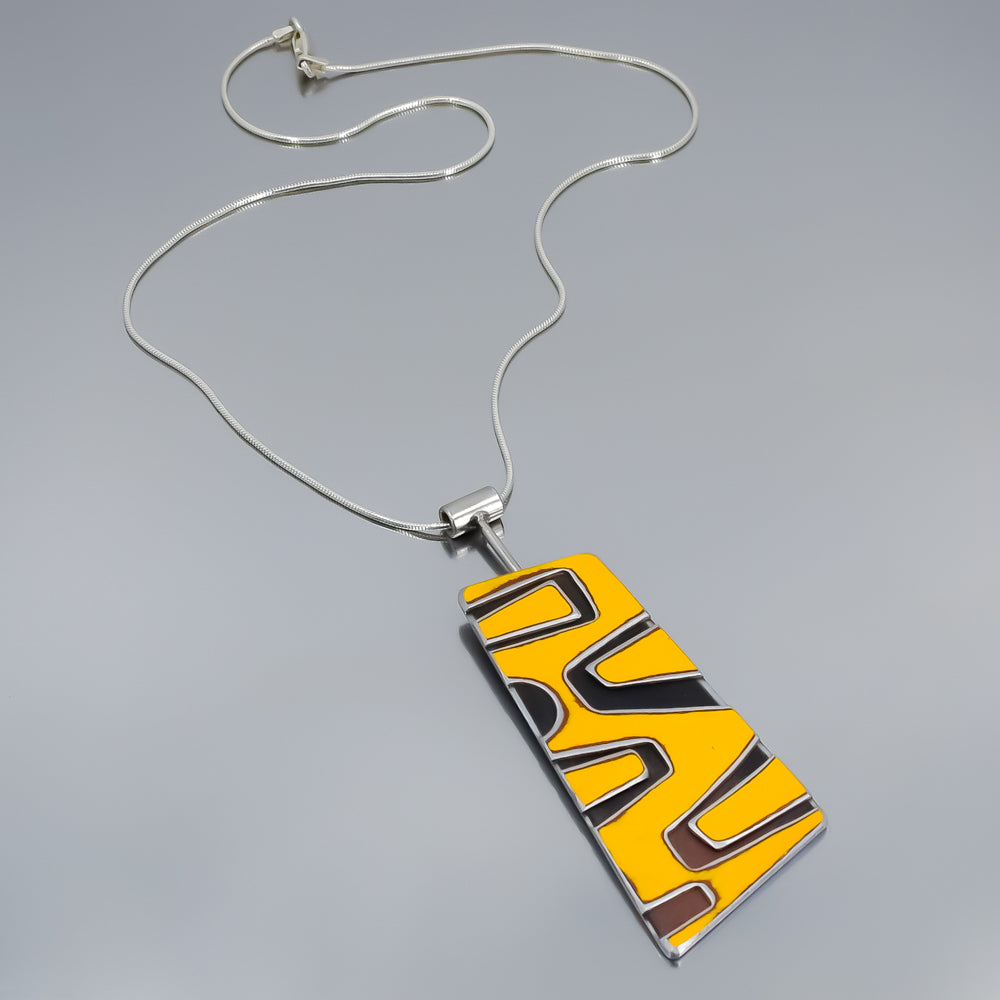 Sterling silver snake chain necklace with a yellow and black abstract enamel pendant, 2 7/8" long and 1 1/8" wide.
