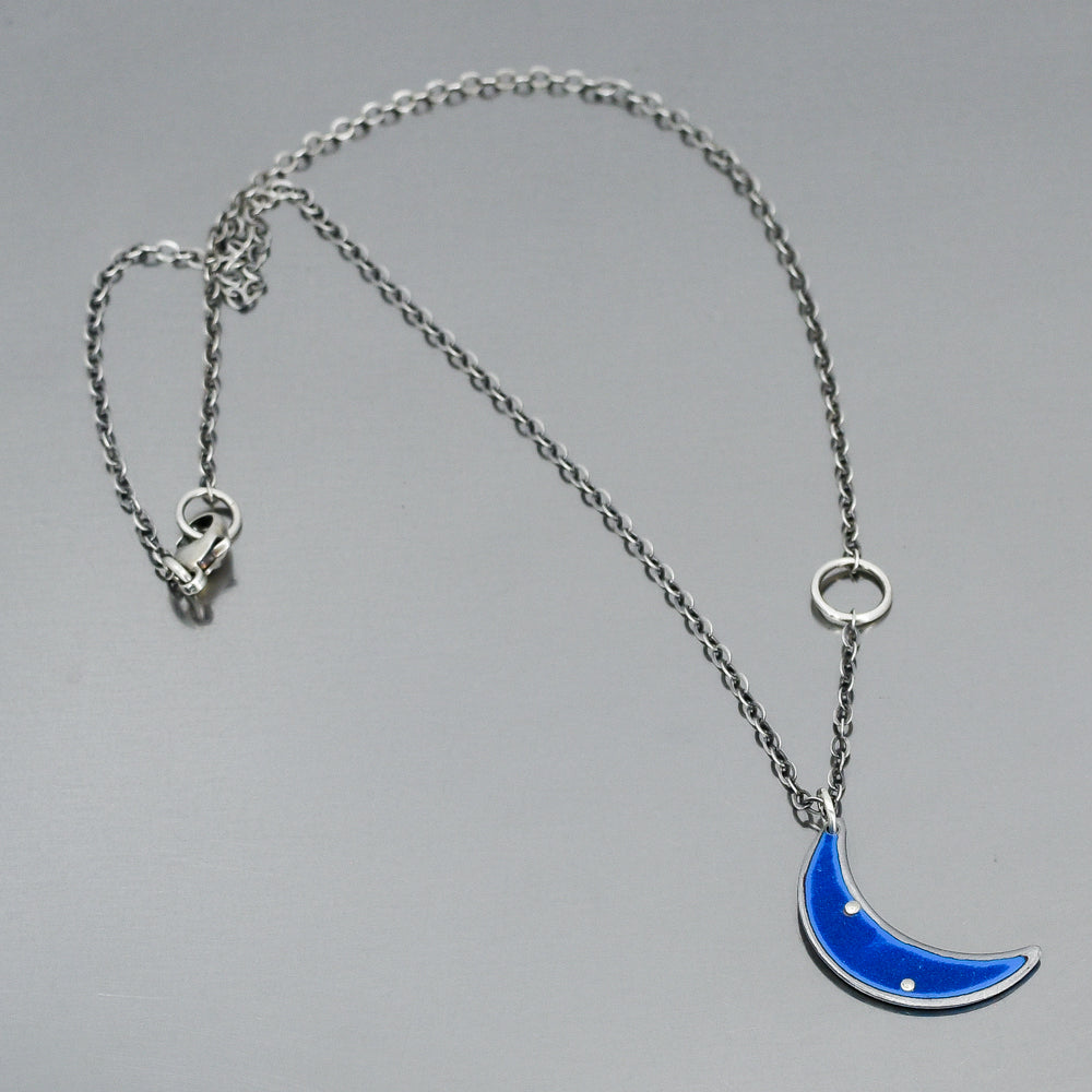 Sterling silver chain necklace with a blue crescent moon pendant on a gray background, model not shown.