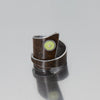 Laurence - Oldsmobile & Plymouth: A handcrafted, wide rustic silver ring with a wrap-around design, featuring a small round yellow-green accent inspired by vintage car paint, displayed on a reflective gray surface.