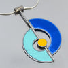 The Shirley - Ford & Dodge is a modern pendant necklace with blue and teal semicircles inspired by vintage car paint, a metallic divider, yellow center detail, and hangs from a sterling silver chain.