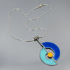 Shirley - Ford & Dodge: A sterling silver necklace with a geometric pendant featuring vintage car paint blues and a yellow center in an abstract design. Arrives on a gray background. Enjoy free shipping with your order!.