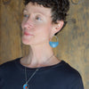 Woman wearing Faye - Dodge pickup sterling silver earrings with blue half-circle design against wood background
