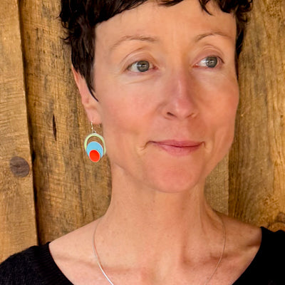 Evelyn - Plymouth, Oldsmobile, Ford earrings worn by model with rustic wooden background visible.