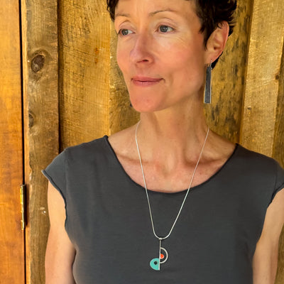 Beverly - Chevy, GMC, Ford pendant necklace worn by woman with sterling silver chain and wooden background.