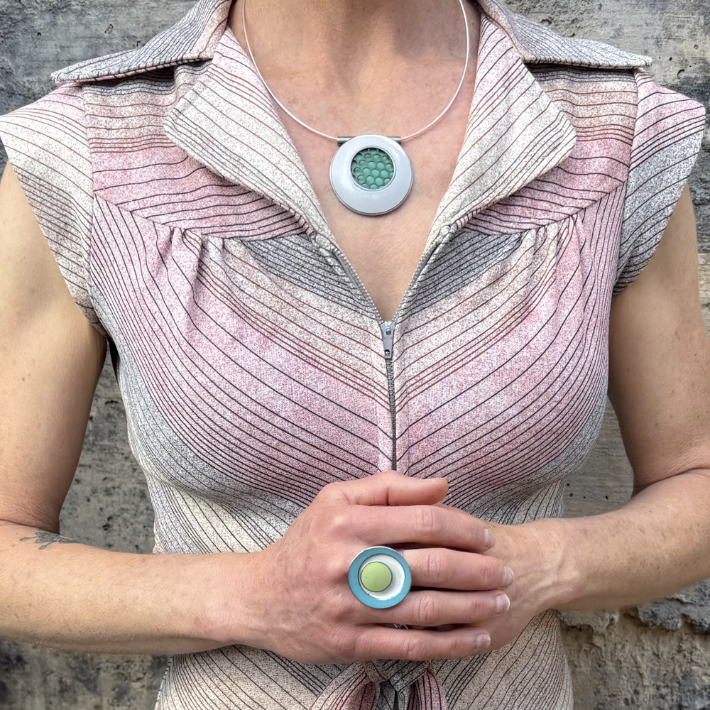 Abella - Ford, Audi, Plymouth ring with original car paint in turquoise, white, and green worn on hand.