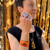 Woman wearing Vern - Ford adjustable bracelet in orange with Ford truck paint, posing against wooden background.