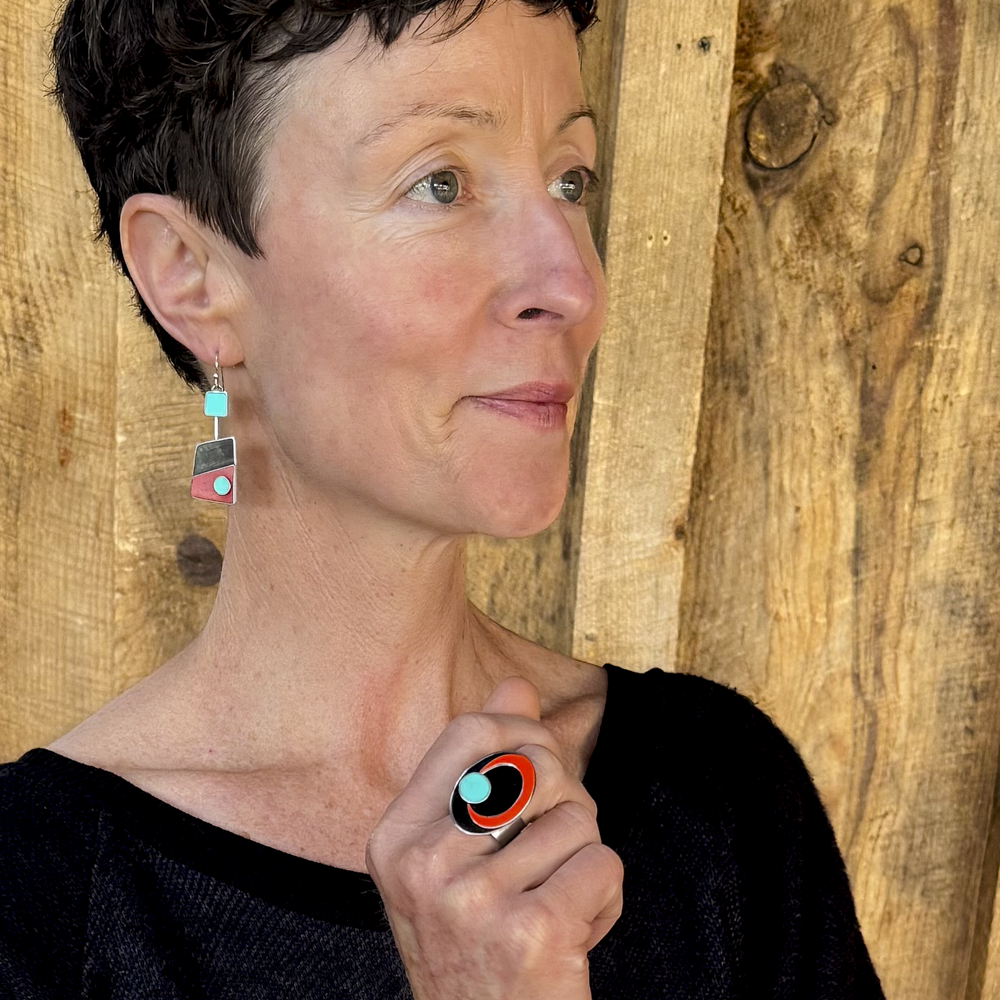Woman wearing Ada - Dodge, GMC, Mercury earrings and ring in turquoise, black, and red with silver ear wires.