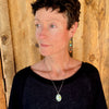 Woman modeling jewelry, wearing a bright, colorful, unique, original necklace and earrings.
handmade using vintage car parts with the original car paint intact. Joyride Jewelry. Jewelry made from vintage car parts. sustainable, recycled 

