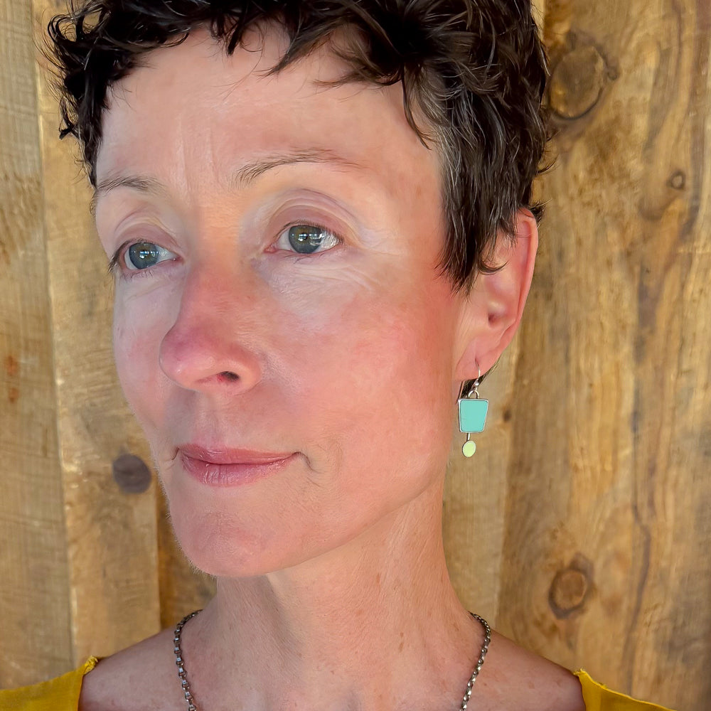 Woman modeling jewelry, wearing a bright, colorful, unique, original necklace and earrings.
handmade using vintage car parts with the original car paint intact. Joyride Jewelry. Jewelry made from vintage car parts. sustainable, recycled 

