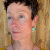 Woman modeling jewelry, wearing a bright, colorful, unique, original necklace and earrings.
handmade using vintage car parts with the original car paint intact. Joyride Jewelry. Jewelry made from vintage car parts. sustainable, recycled 

