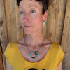 Woman modeling jewelry, wearing a bright, colorful, unique, original necklace and earrings.
handmade using vintage car parts with the original car paint intact. Joyride Jewelry. Jewelry made from vintage car parts. sustainable, recycled 

