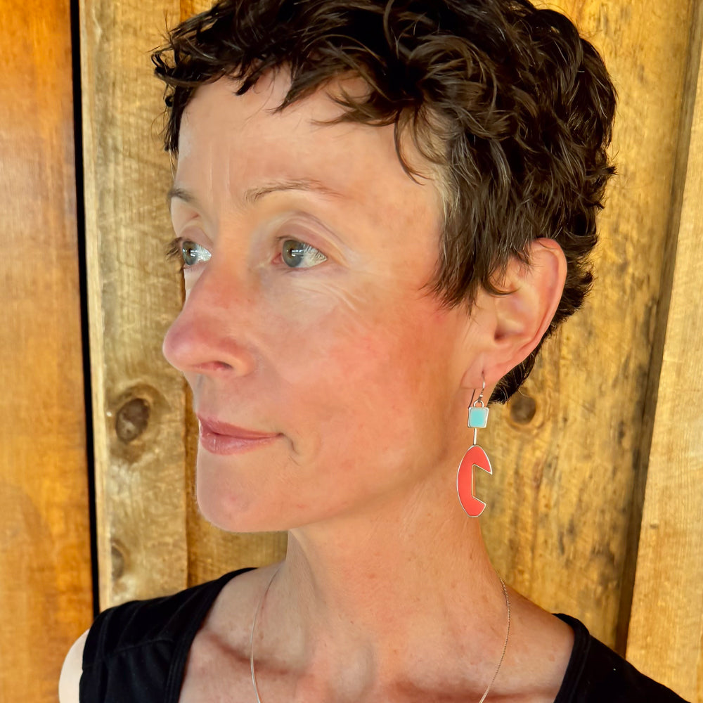 Woman modeling jewelry, wearing a bright, colorful, unique, original necklace and earrings.
handmade using vintage car parts with the original car paint intact. Joyride Jewelry. Jewelry made from vintage car parts. sustainable, recycled 


