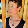 Woman modeling jewelry, wearing a bright, colorful, unique, original necklace and earrings.
handmade using vintage car parts with the original car paint intact. Joyride Jewelry. Jewelry made from vintage car parts. sustainable, recycled 


