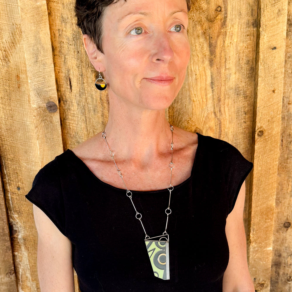Woman modeling jewelry, wearing a bright, colorful, unique, original necklace and earrings.
handmade using vintage car parts with the original car paint intact. Joyride Jewelry. Jewelry made from vintage car parts. sustainable, recycled 

