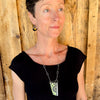 Woman modeling jewelry, wearing a bright, colorful, unique, original necklace and earrings.
handmade using vintage car parts with the original car paint intact. Joyride Jewelry. Jewelry made from vintage car parts. sustainable, recycled 

