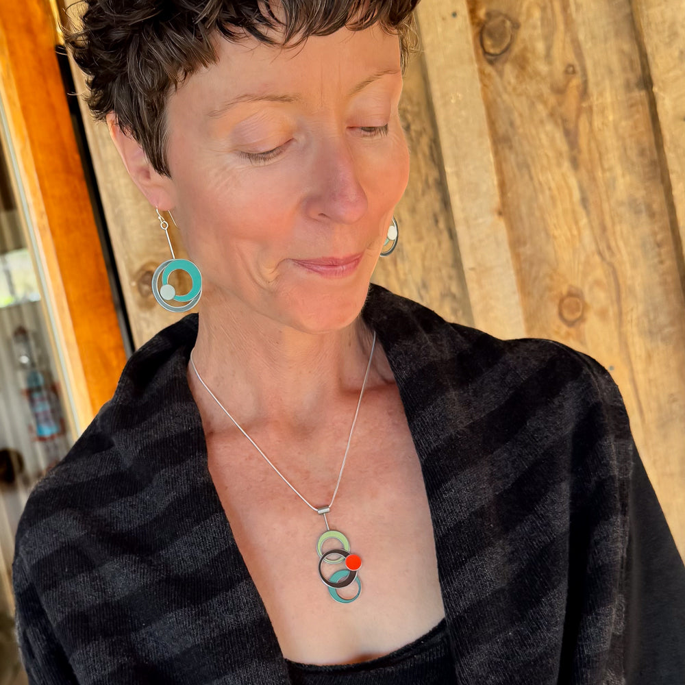 Woman wearing Lorraine pendant necklace made from vintage car paint and matching earrings on sterling silver chain