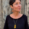Woman wearing Wilma pendant necklace made from 79 International Scout car paint with matching orange earring on sterling silver wire