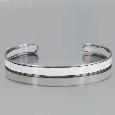 Luz - Audi: made from vintage car parts An elegant, open-ended adjustable cuff with a smooth, polished surface and rounded edges, displayed on a reflective gray background.