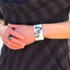 A person wearing the Emmett - Ford adjustable bracelet with geometric designs and matching ring, hands together in front of a black and gray striped garment.