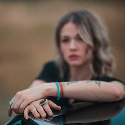 A woman shown modeling a ring and three bracelets made from vintage car parts. Handmade jewelry by Joyride Jewelry.